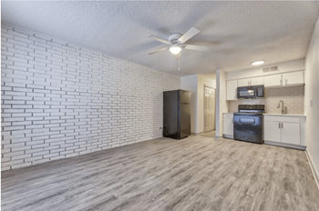 An open living room with a kitchen and a ceiling fan
